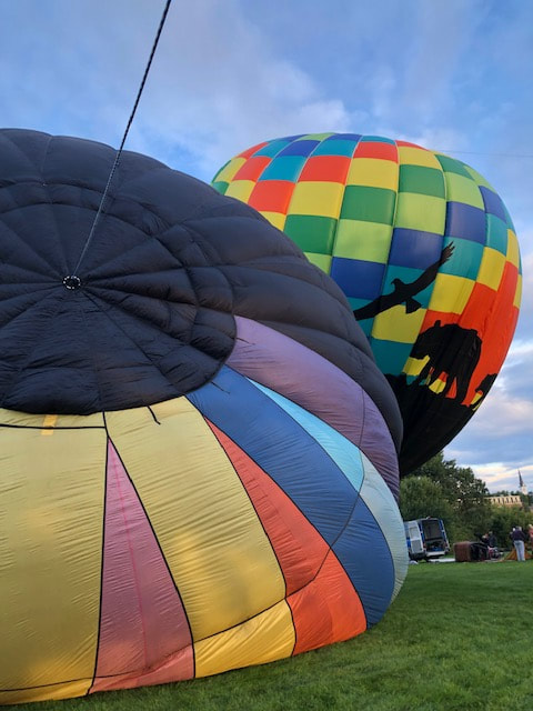 two hot air balloons filling and lifting fromthe ground